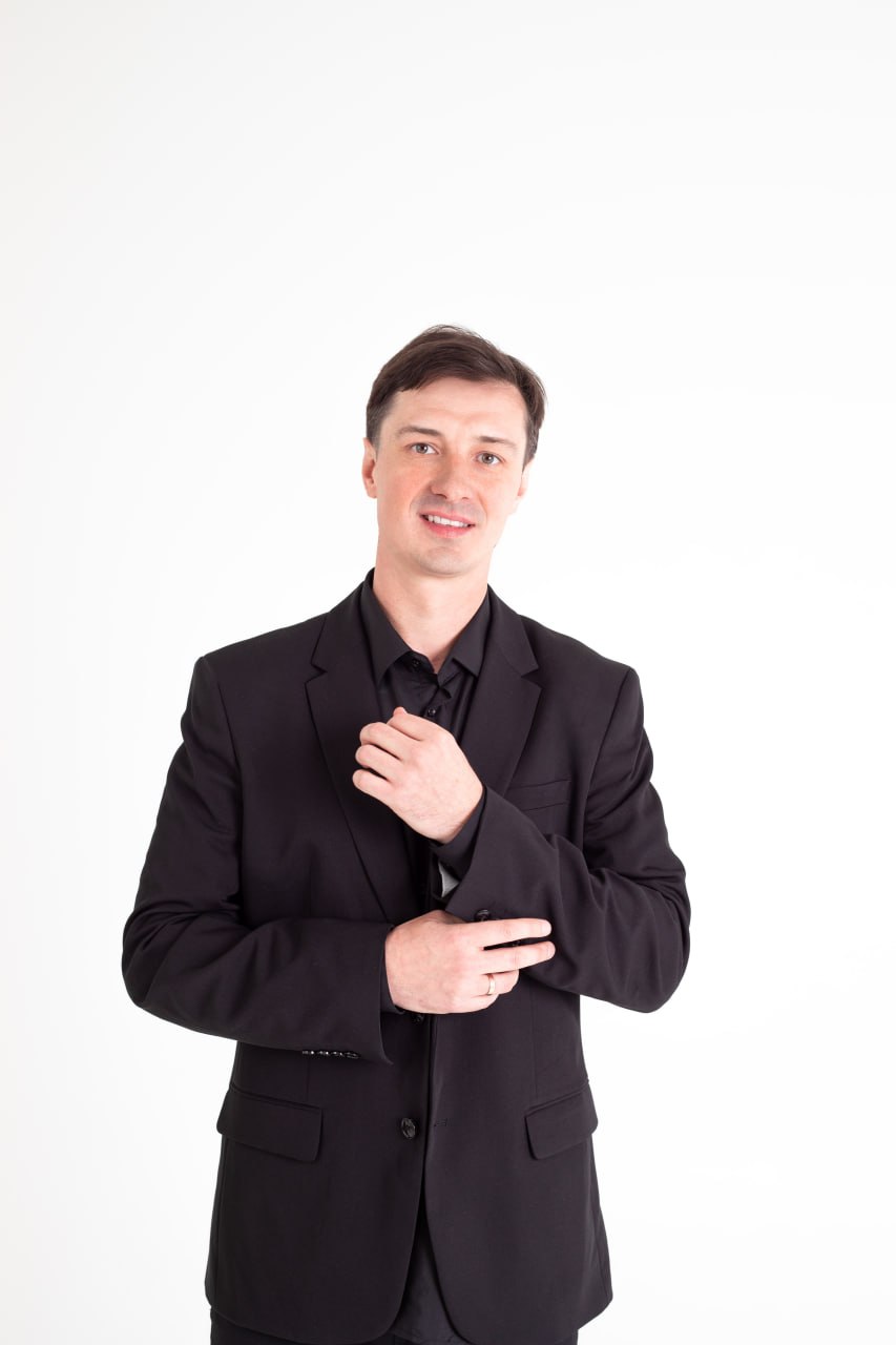 Антон Верт улыбается, стоя в тёмном пиджаке